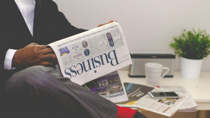 person sitting near table holding newspaper